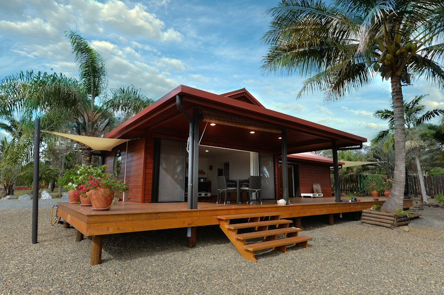 Bungalow de madera con terraza entre palmeras