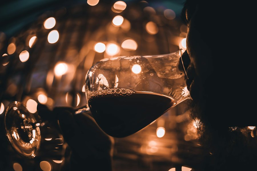 Copa de vino tinto con luces cálidas al fondo
